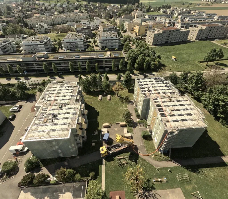 Luftaufnahme: Kies und Substrat werden mit einem Silolastwagen auf die Dächer geblasen