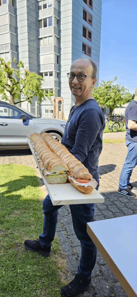 Ein Helfer trägt ein Brett mit langen, belegten Sandwiches für den Apéro