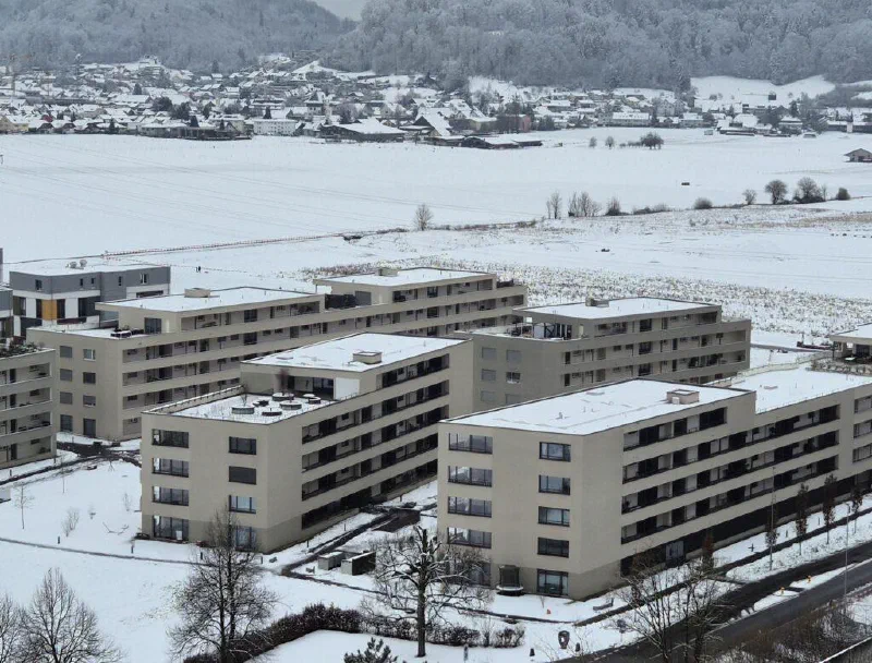 Verschneite Mehrfamilienhäuser am Chrüzweg mit Solaranlagen auf den Flachdächern