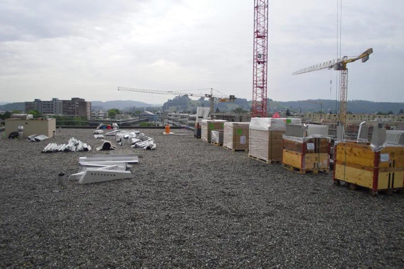 Gelieferte Paletten mit Solarmodulen und Montagematerial auf dem Kiesdach