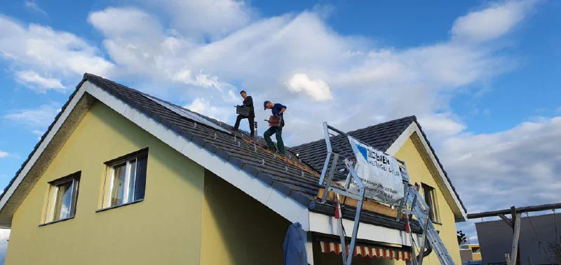 Zwei Monteure verlegen die Montageschienen auf dem Hauptdach