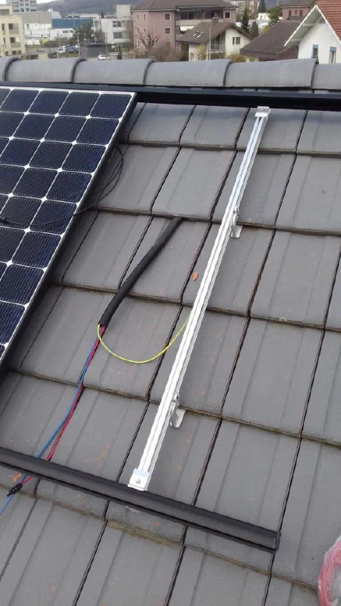 Montageschiene und Verkabelung neben einem Solarmodul auf dem Ziegeldach