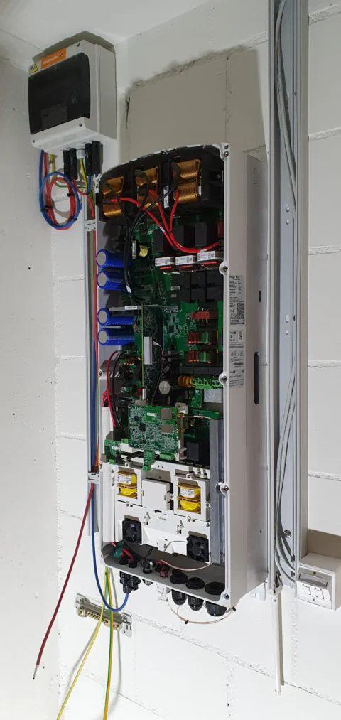 Geöffneter Wechselrichter mit sichtbarer Elektronik an der Kellerwand