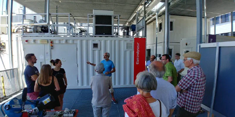 Besuchergruppe vor einem Elektrolyseur-Container am PSI